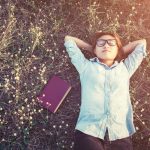 Young hipster woman lying in flower field after she tired for re