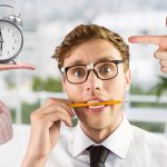 Worried businessman with hand pointing and alarm clock